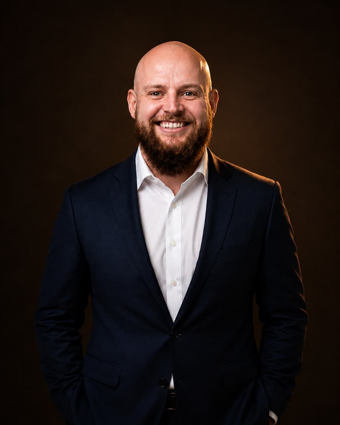 Erik Mollen, photographed in a navy suit against a dark ground.